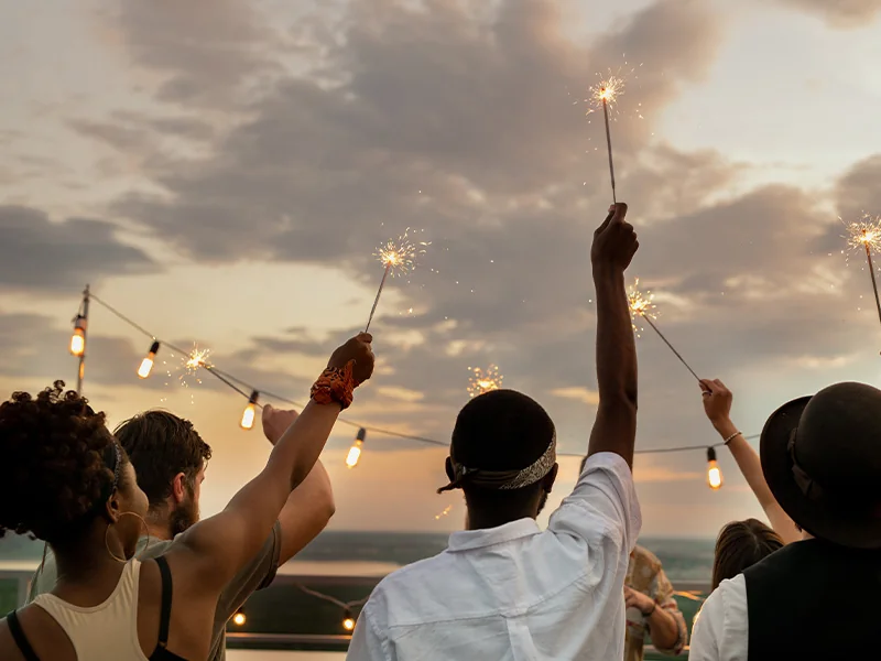 People raising sparklers together at sunset