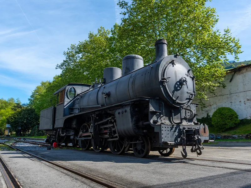 A preserved black steam locomotive beside railroad tracks.