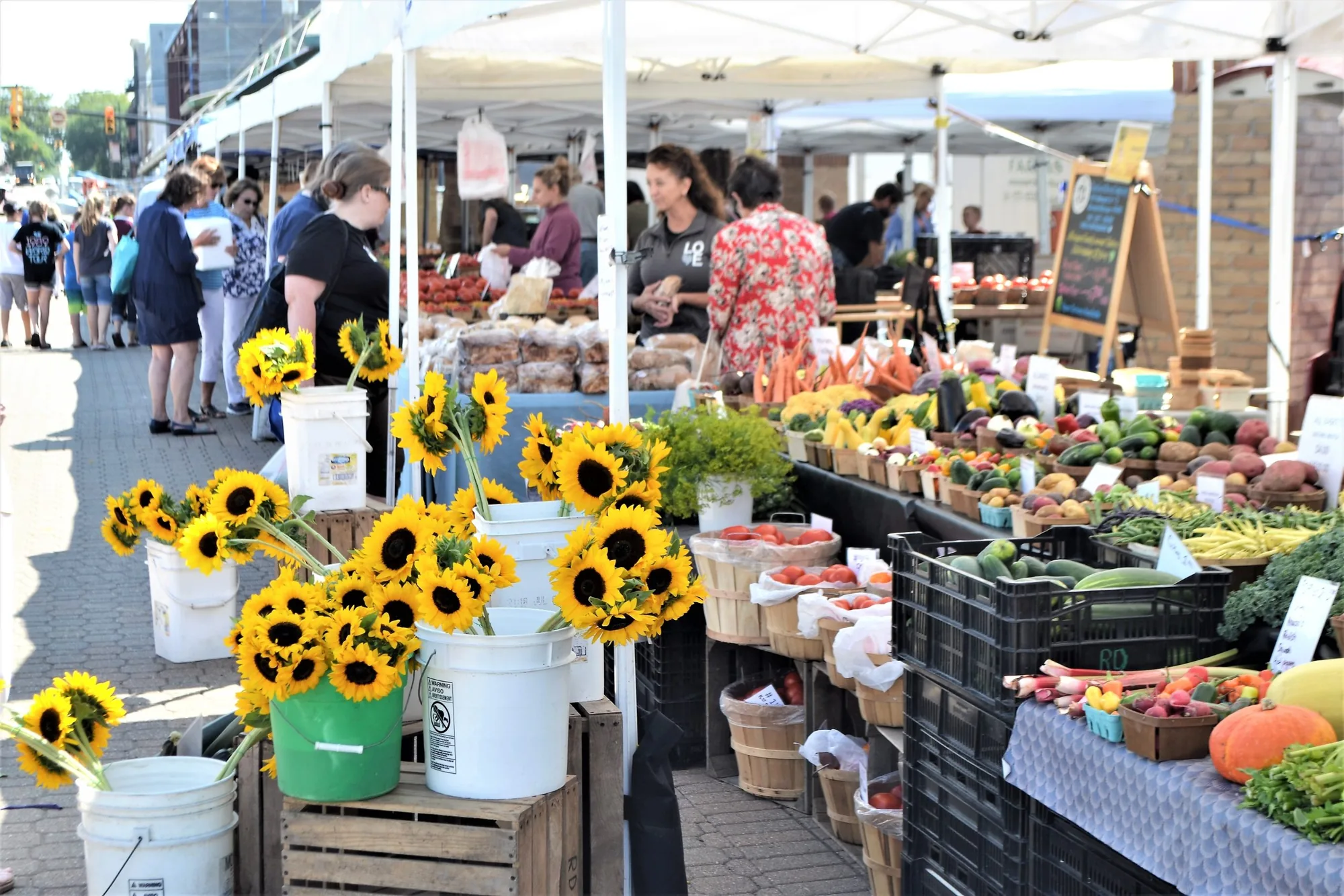 Sunflowers and fresh produce at an outdoor farmers market.